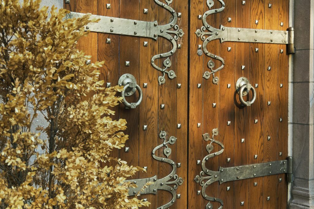 Close-up of a decorative wooden door with intricate iron designs and circular handles.