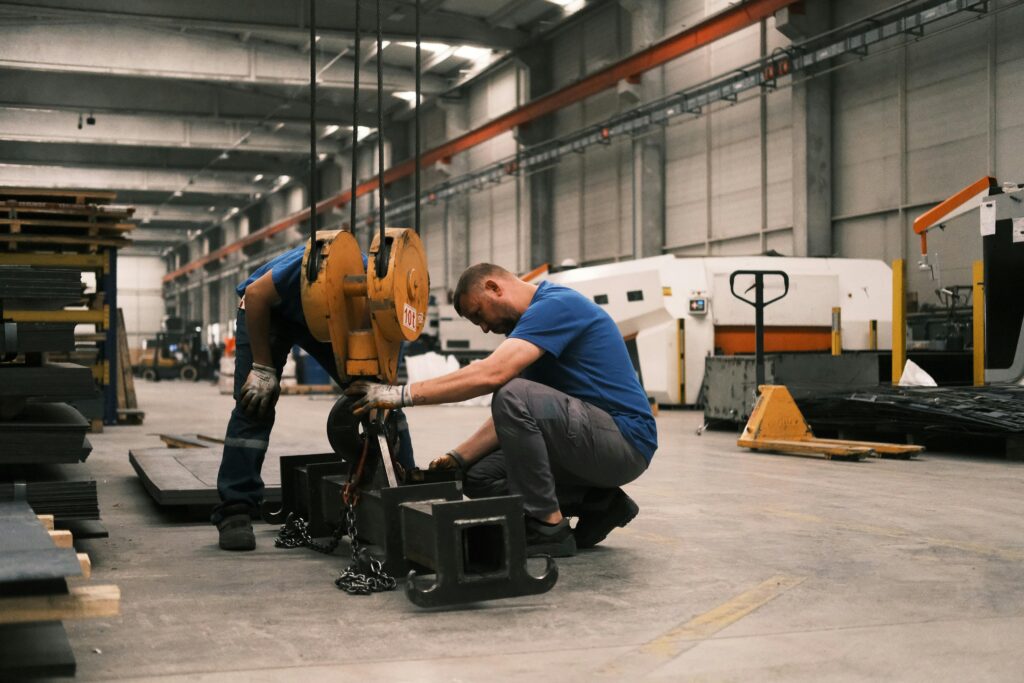 Two workers adjust a heavy-duty crane in a manufacturing plant in Konya, Türkiye.