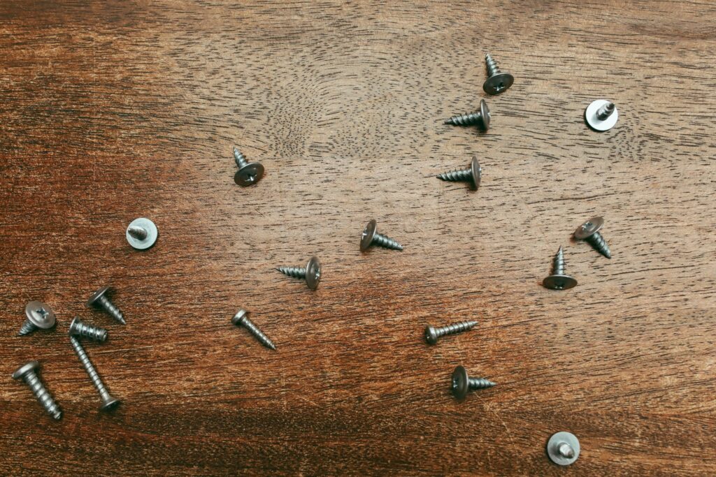 Overhead view of various screws scattered on a wooden surface, ideal for construction themes.